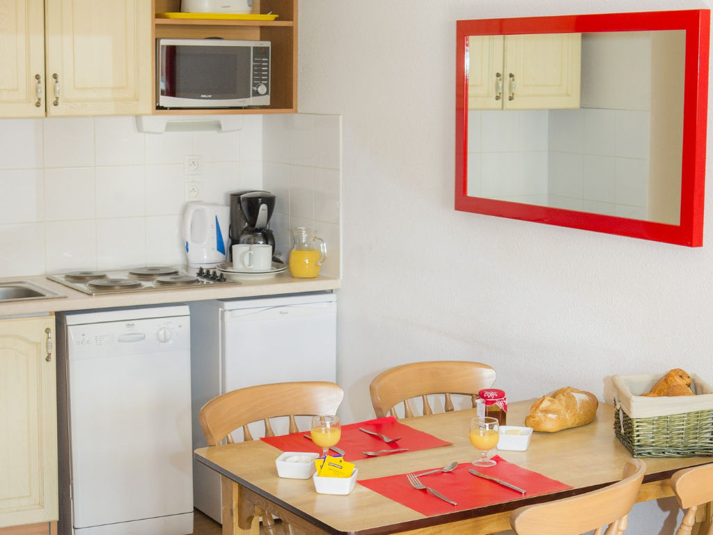 image Fitted kitchen with dishwasher, hob, fridge and microwave beside a dining table.