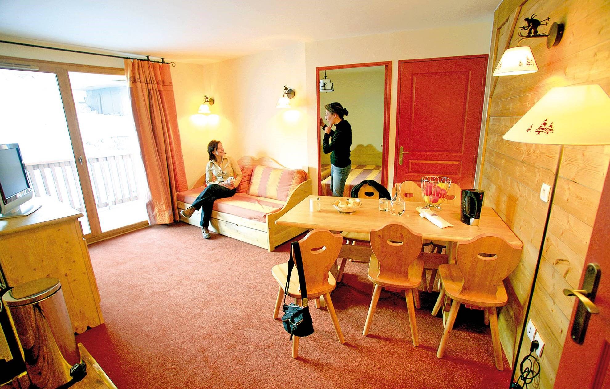 image Living area with a sofa, dining table and balcony door.