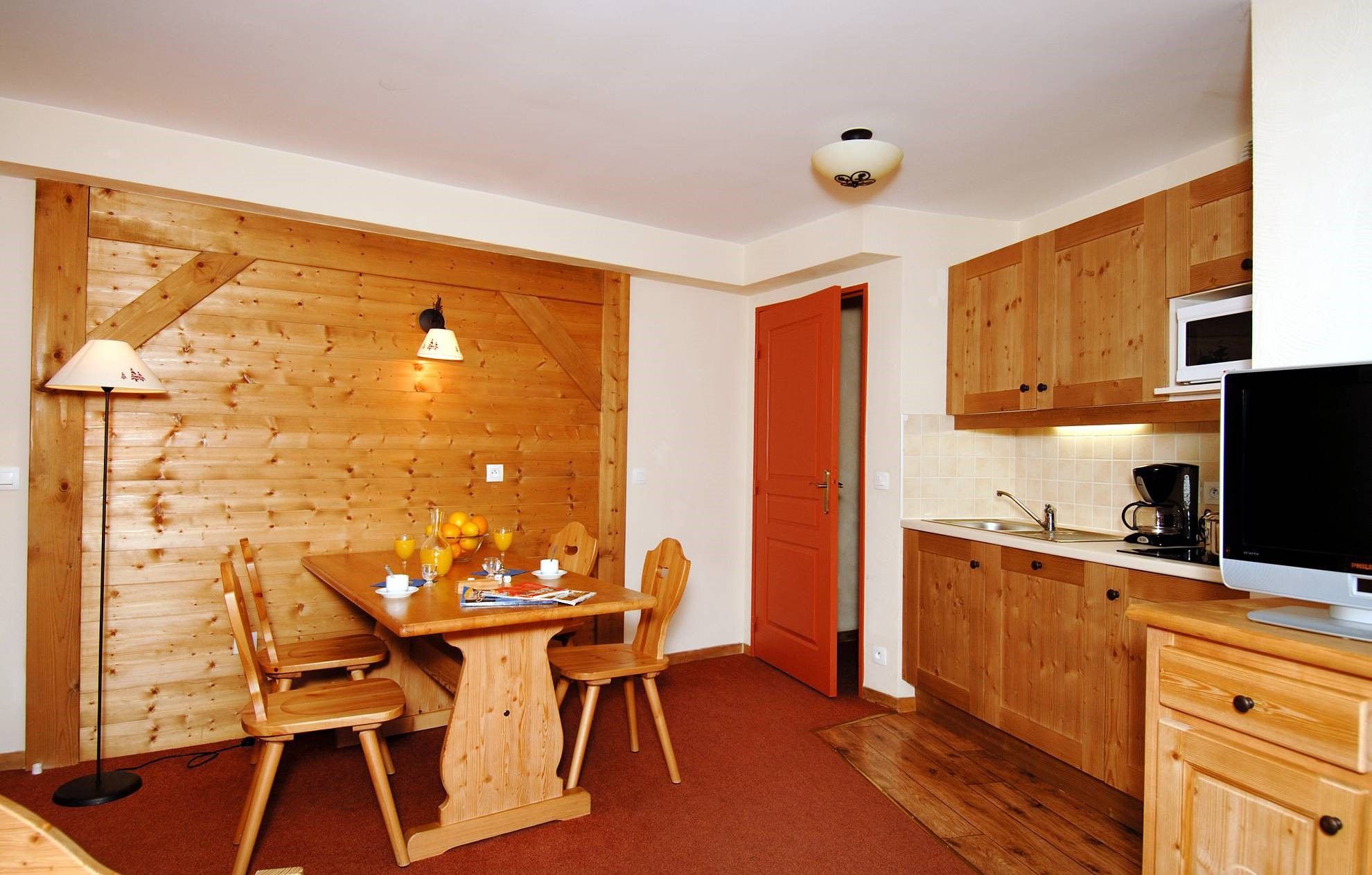 image Wooden dining setup and kitchenette in a light room.