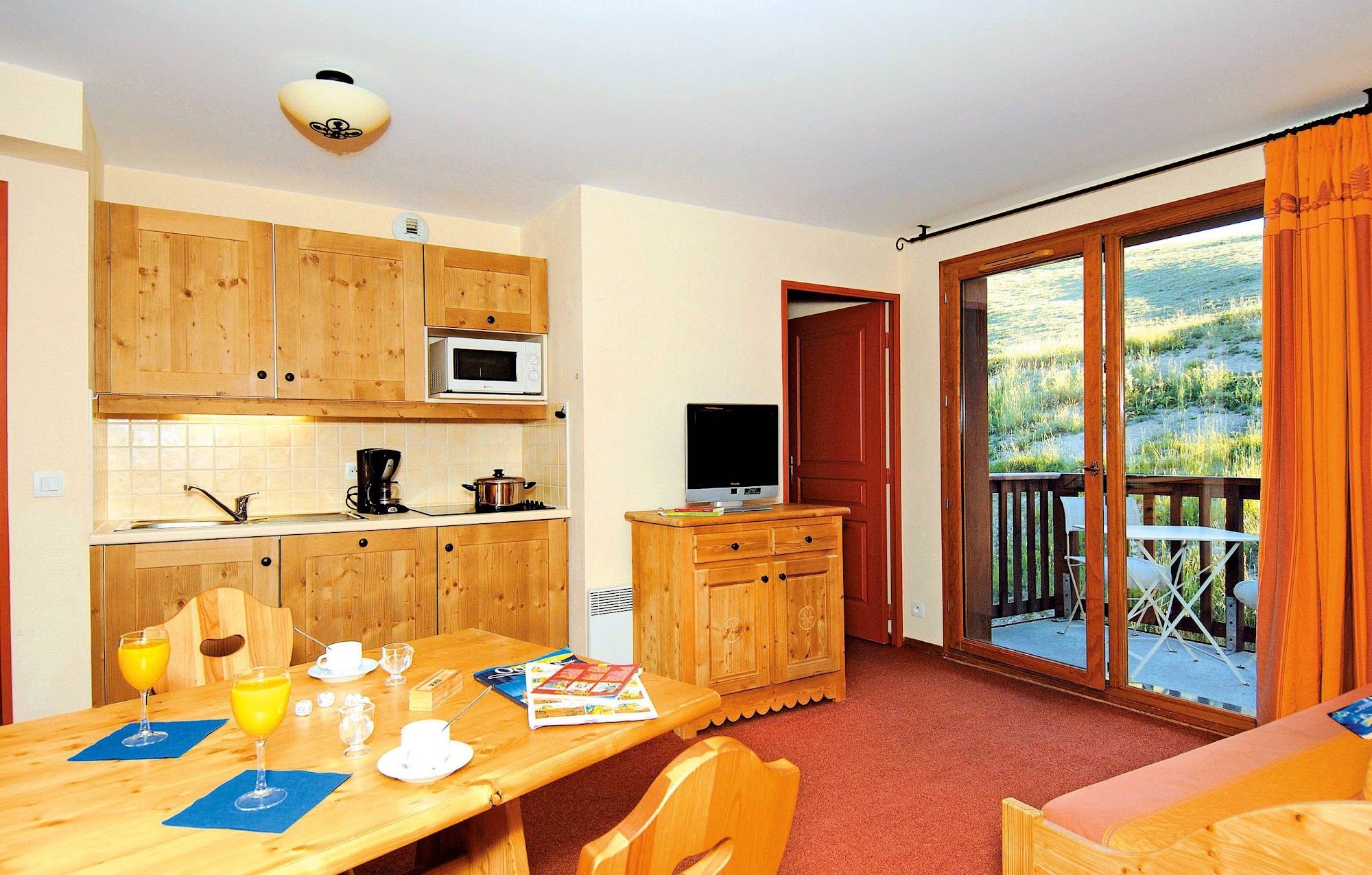image Small kitchenette with wooden cabinets and appliances.