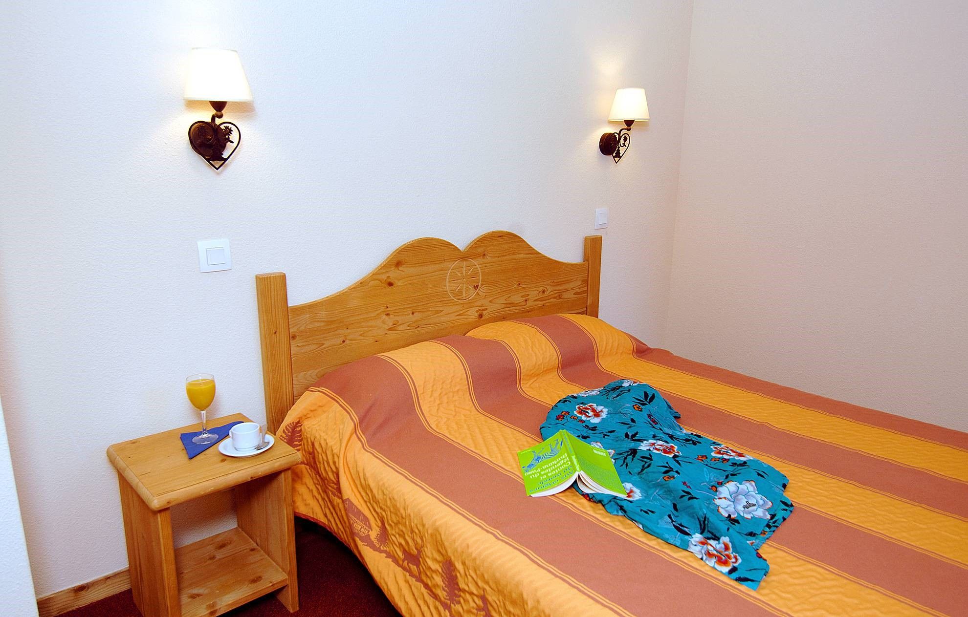 image Bedroom with orange and green bedding and a small table.