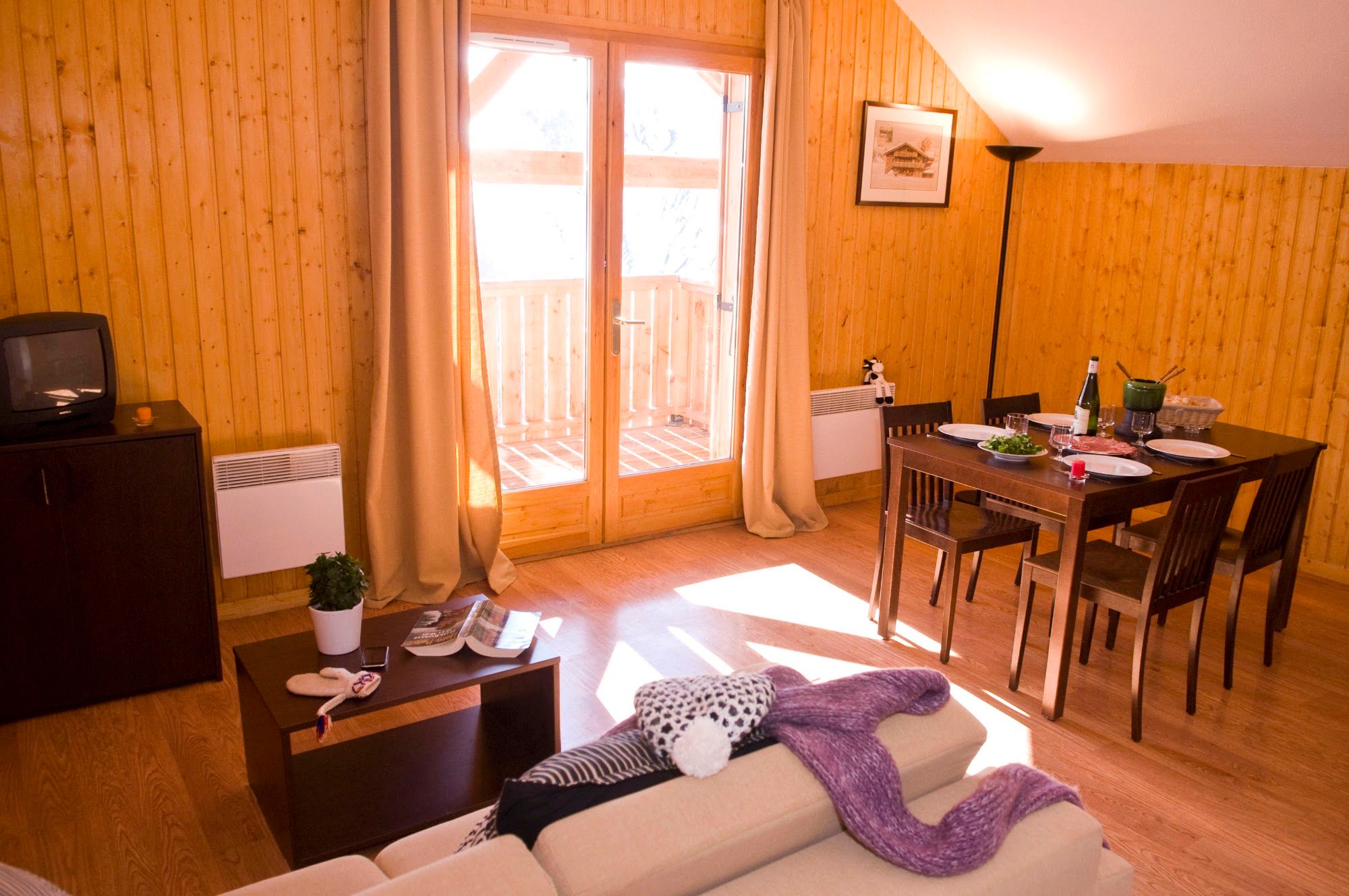 image Unit living/dining room, wood-paneled, balcony doors open, table set