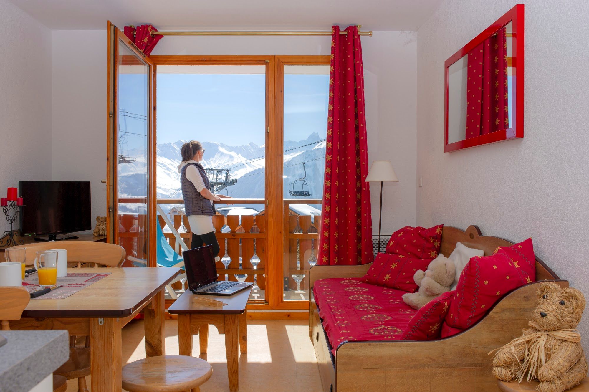 image A woman stands by large windows overlooking snowy mountains and ski lifts.