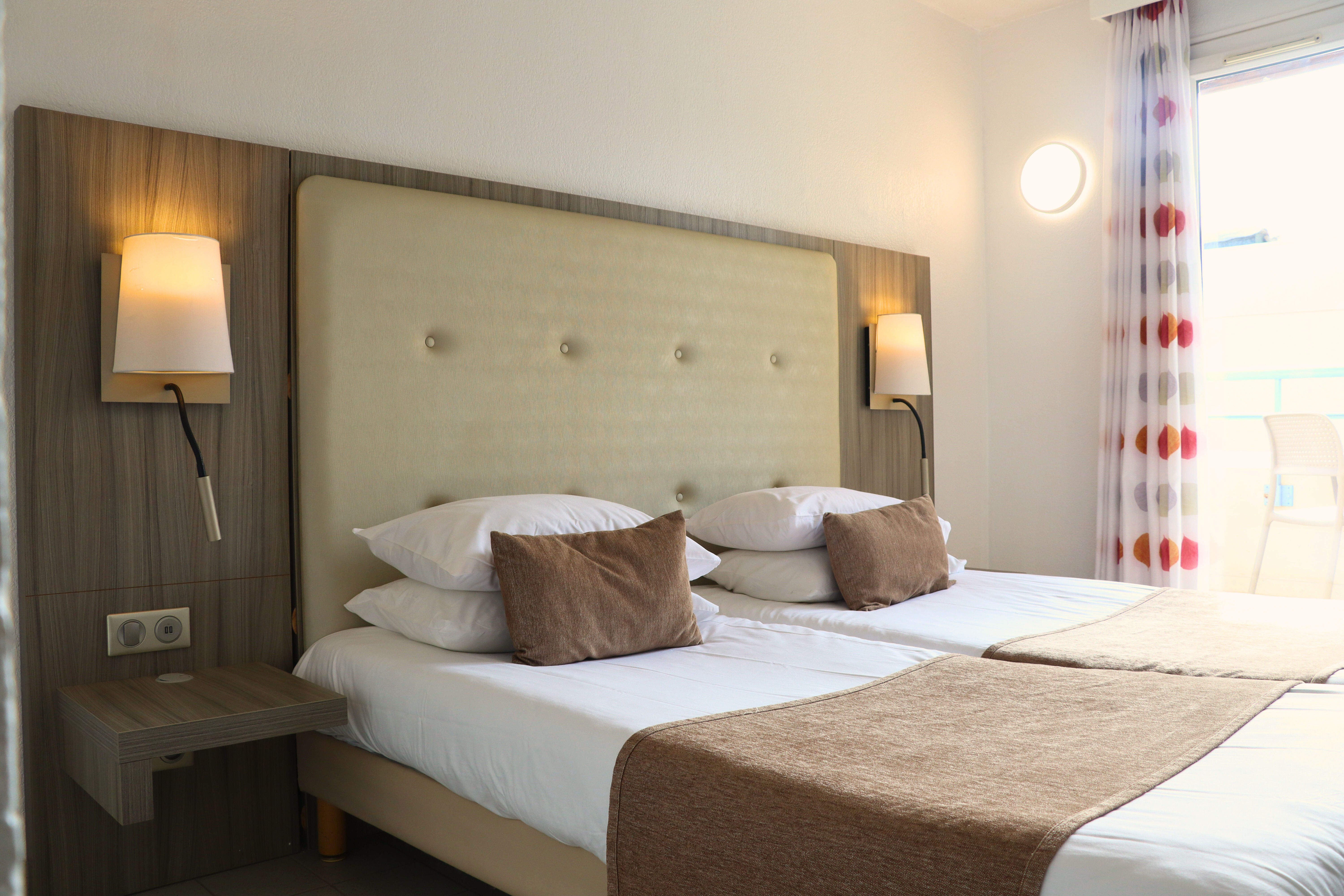 image Two beds with pillows and bedside lamps.