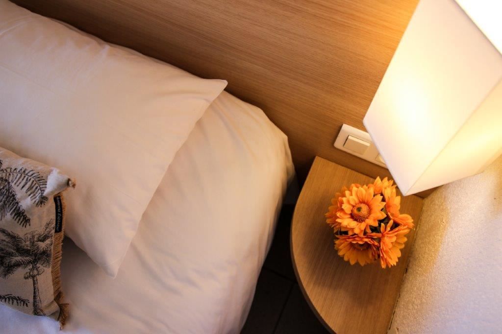 image Corner of a bed with a pillow and lamp.