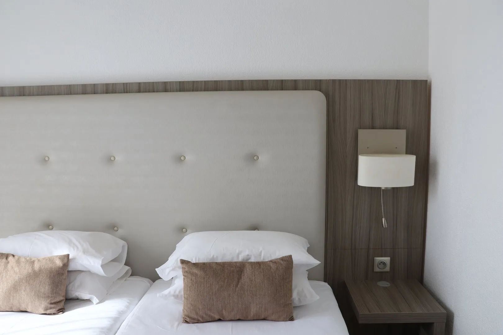 image Two beds with pillows and bedside lamp.