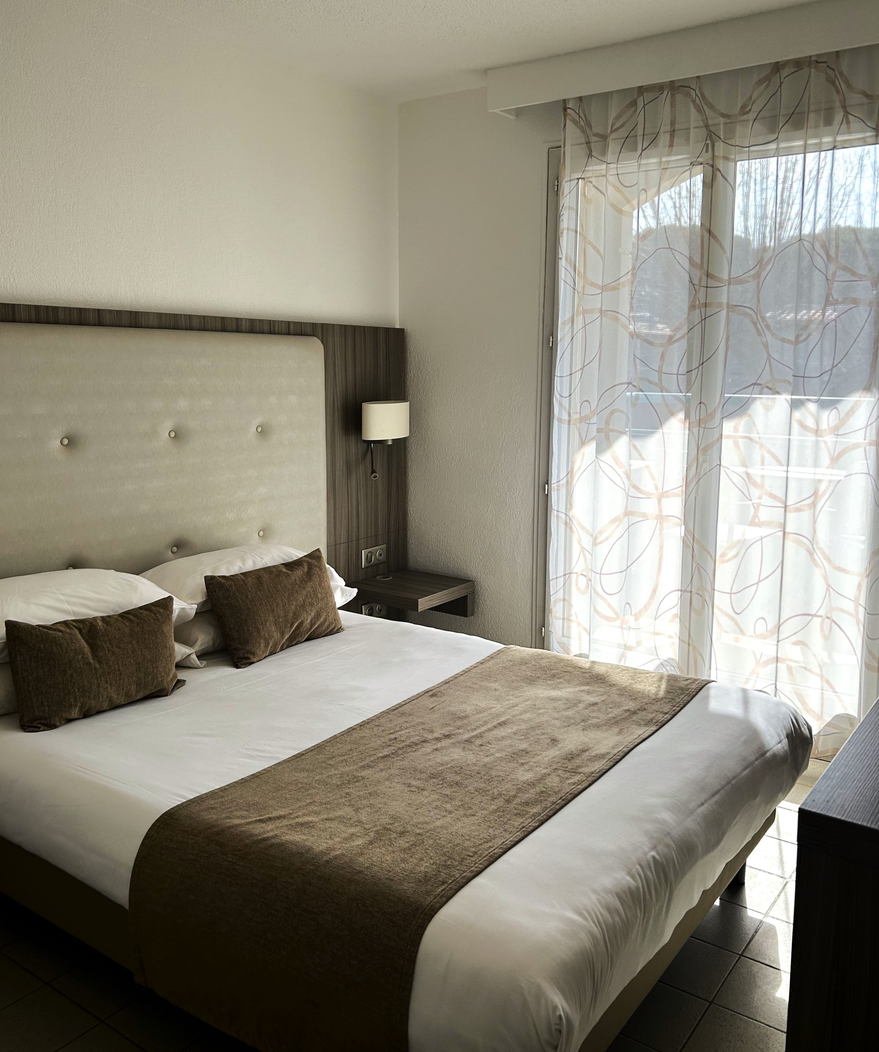 image Large bed with decorative pillows near a window.