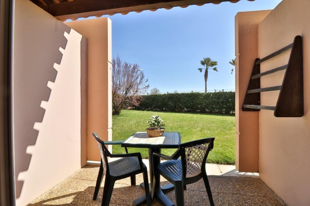 image Outdoor seating area with a table and greenery view.