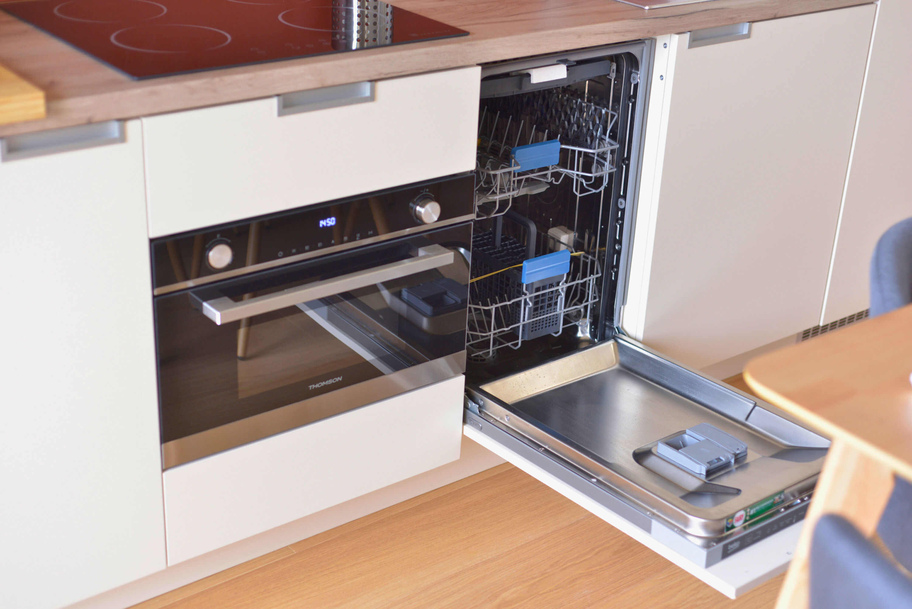 image Kitchen area with an open dishwasher and stove.