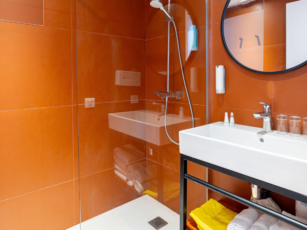image Bathroom with a shower, round mirror, and towels.