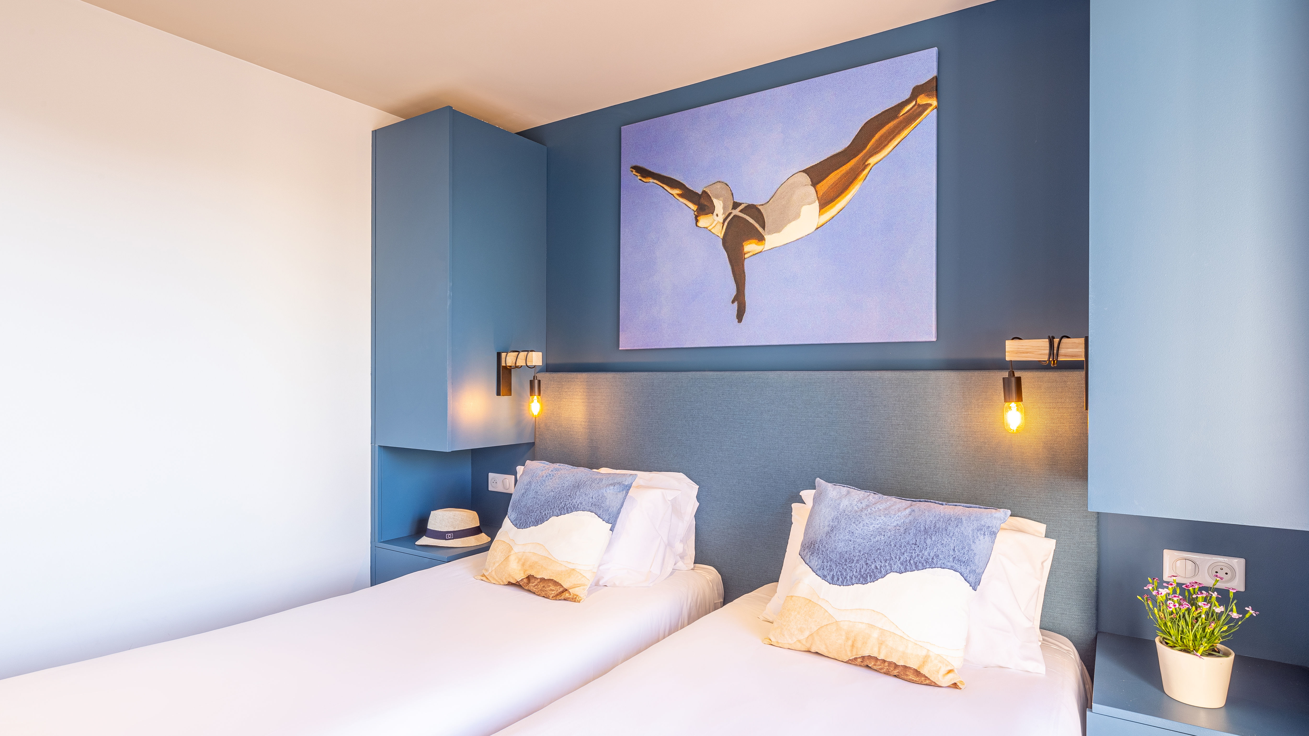 image Bedroom with two beds, a blue accent wall, and lamps.
