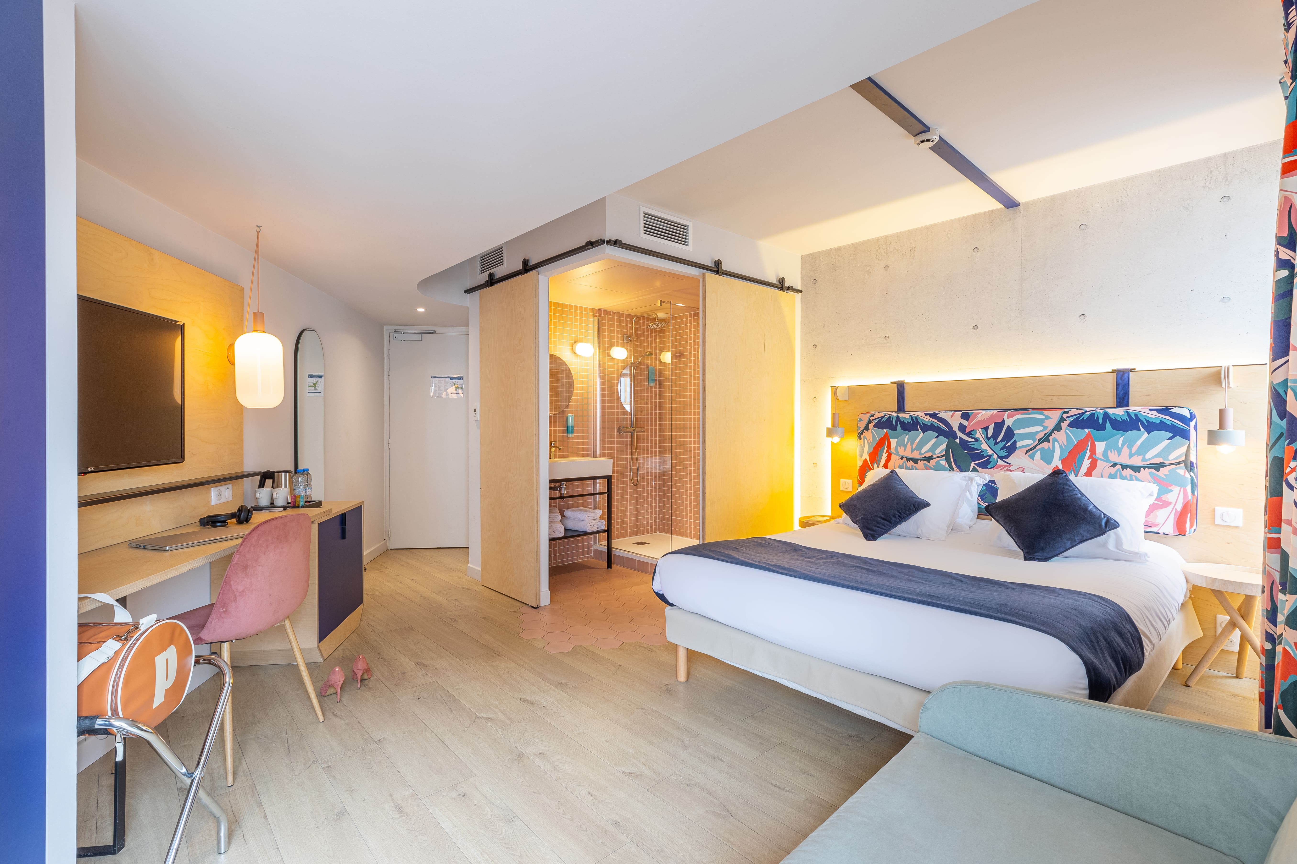 image A sliding barn door reveals the orange-tiled walk-in shower just steps from the extra-wide bed and daybed