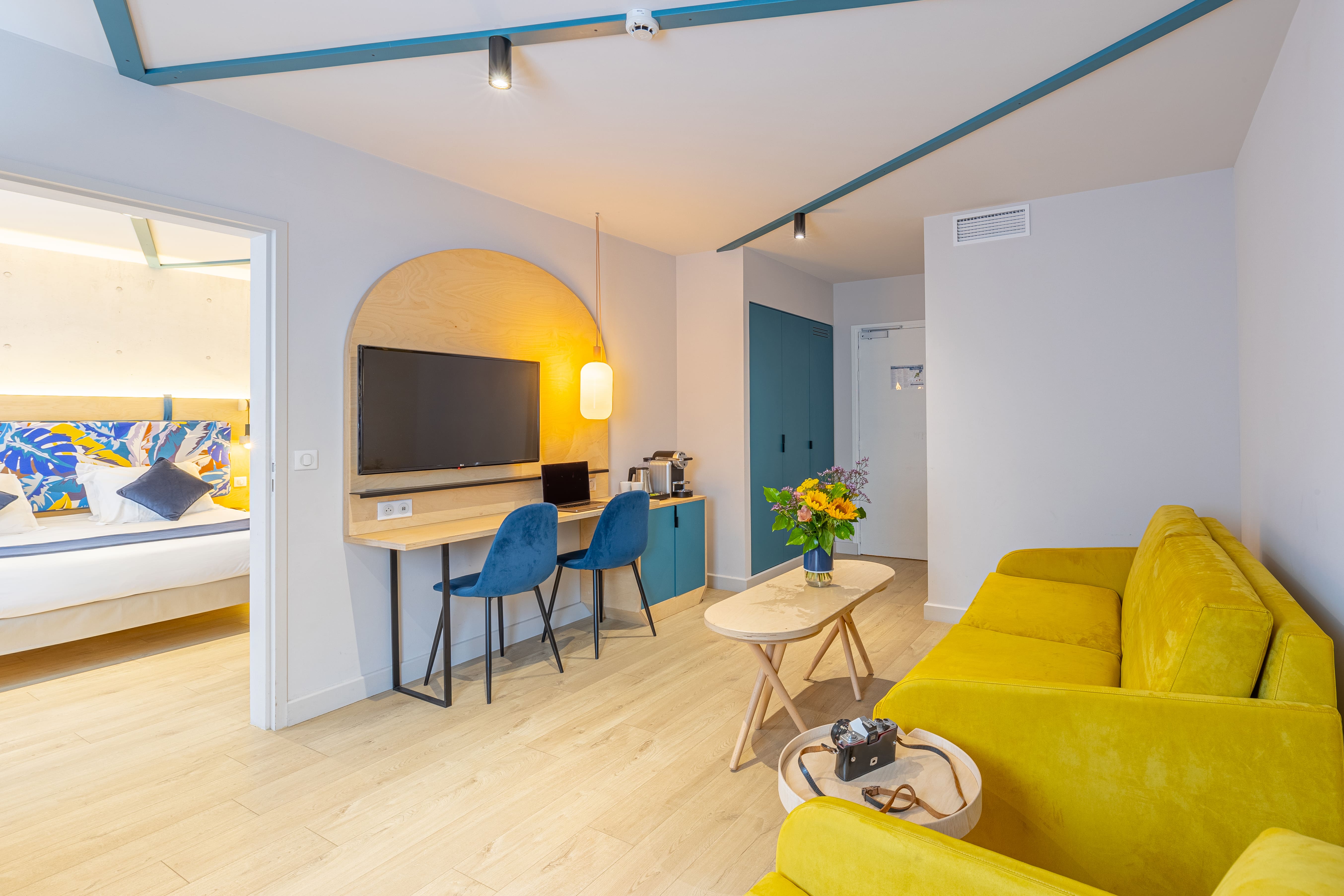 image An open doorway connects the bedroom to the living area, where a coffee machine sits ready beside the desk