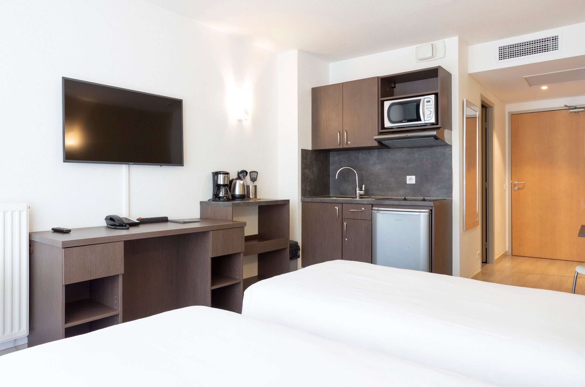 image Studio with two beds, desk, kitchen area, and television