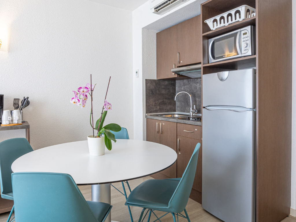image Kitchen area with round table, chairs, and refrigerator