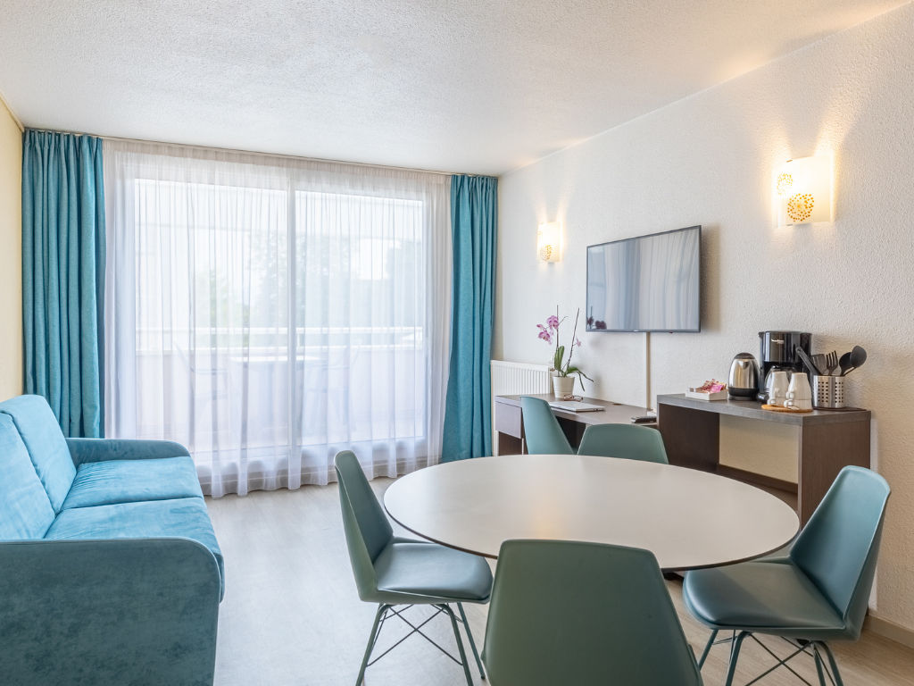 image Living area with dining table, blue couch, and TV.