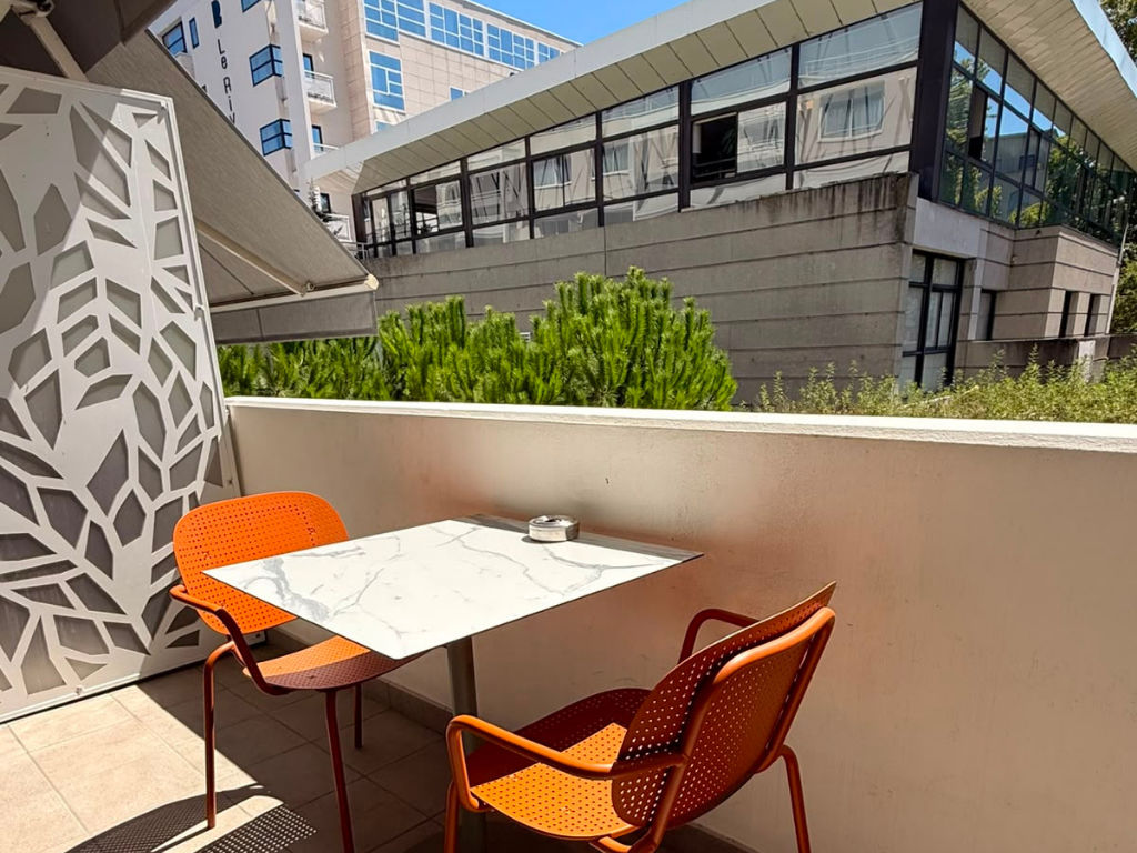 image Outdoor balcony with a table and orange chairs.