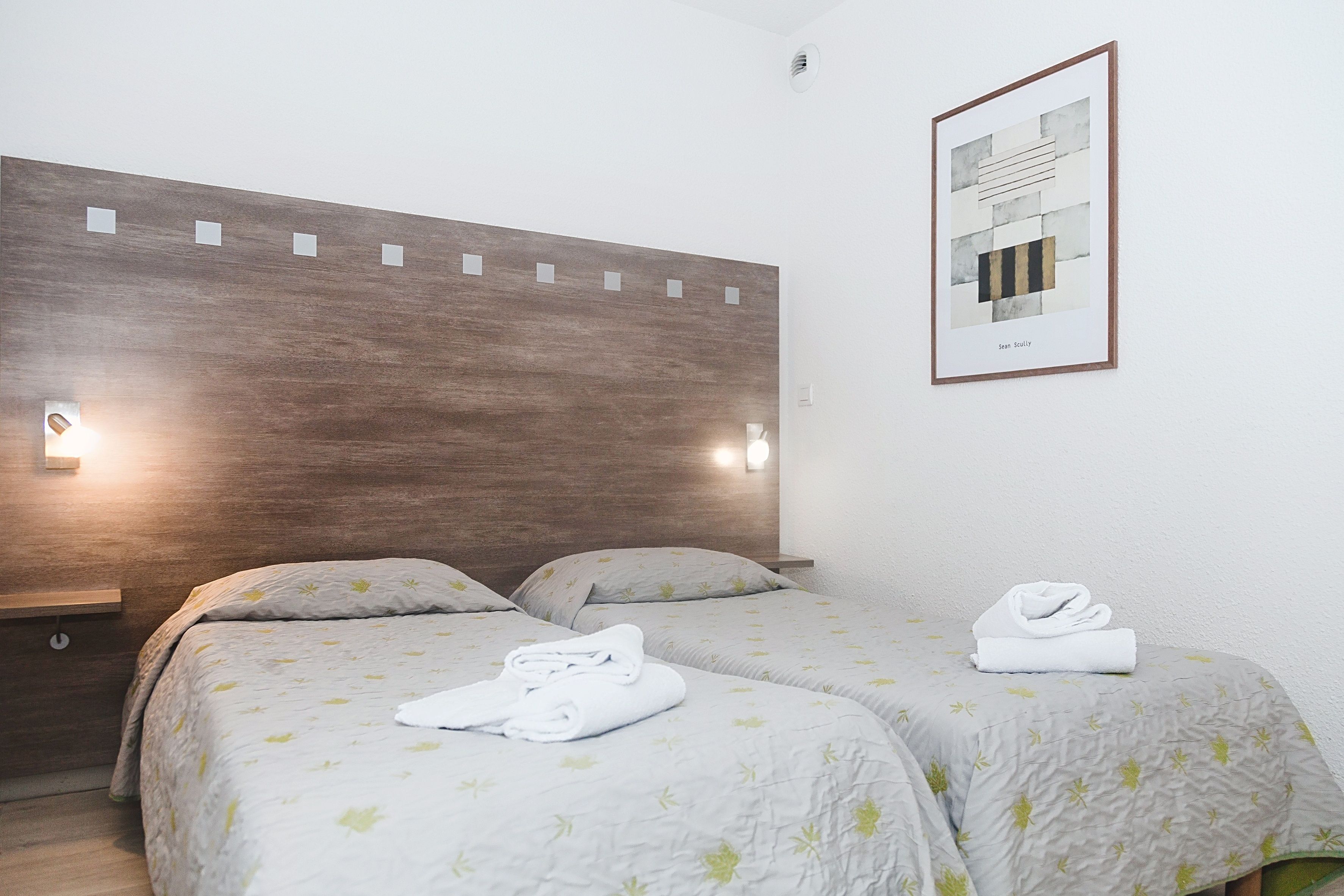 image Bedroom detail with two beds and framed wall art.