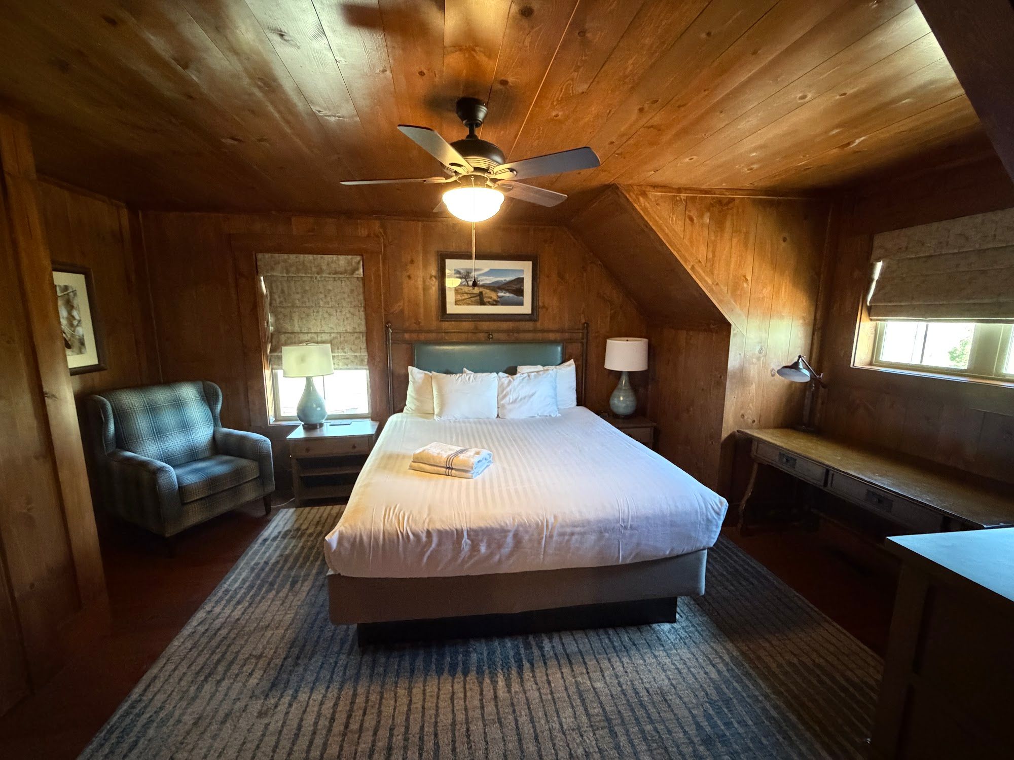 image Bedroom with king bed, chair, and desk near a window.