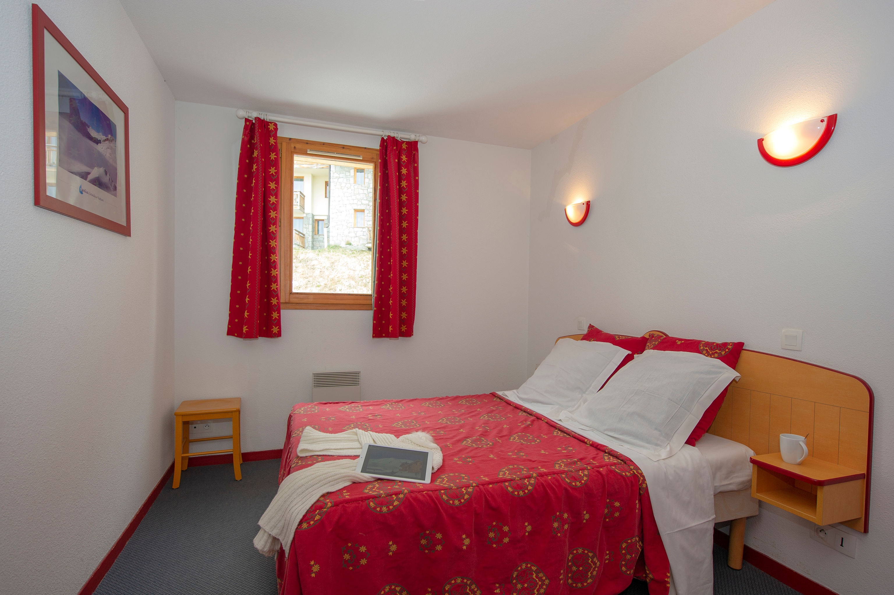 image Red curtains and a nightstand complete the main bedroom.