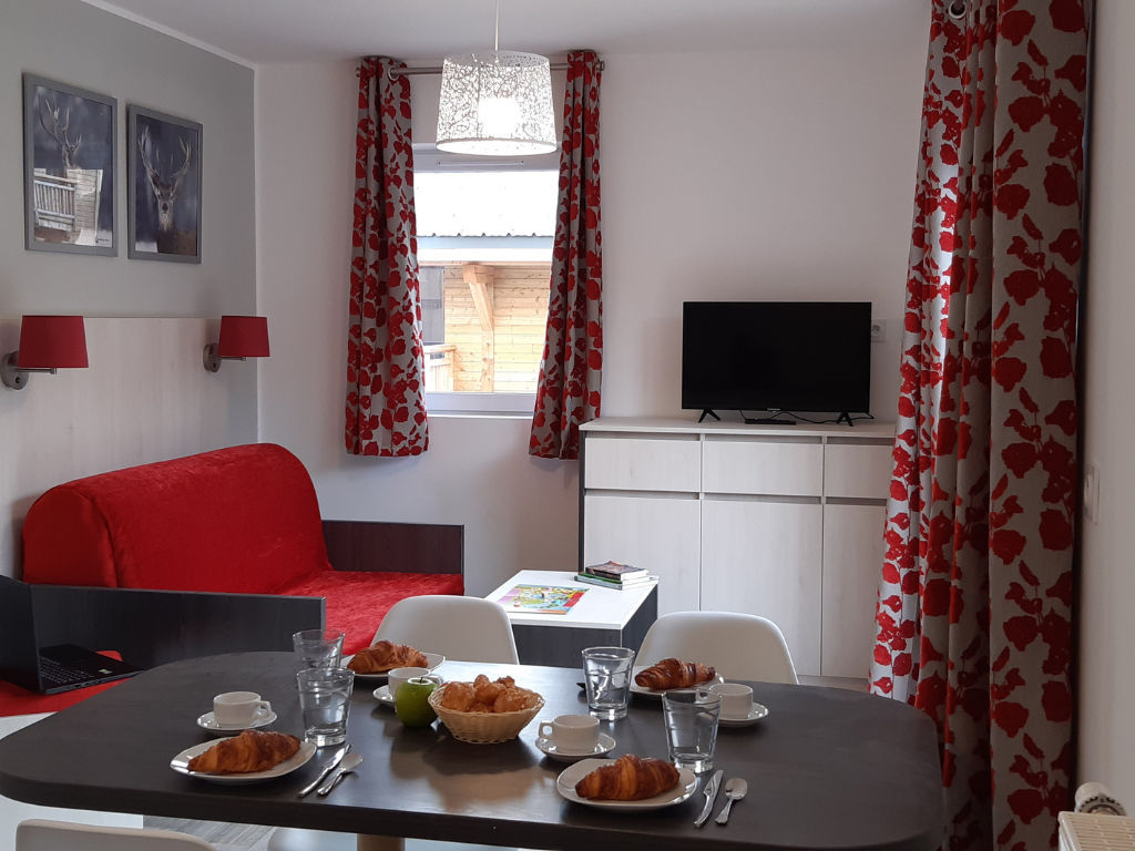 image Fresh croissants and coffee sit on the dining table, with the red sofa and TV close by.