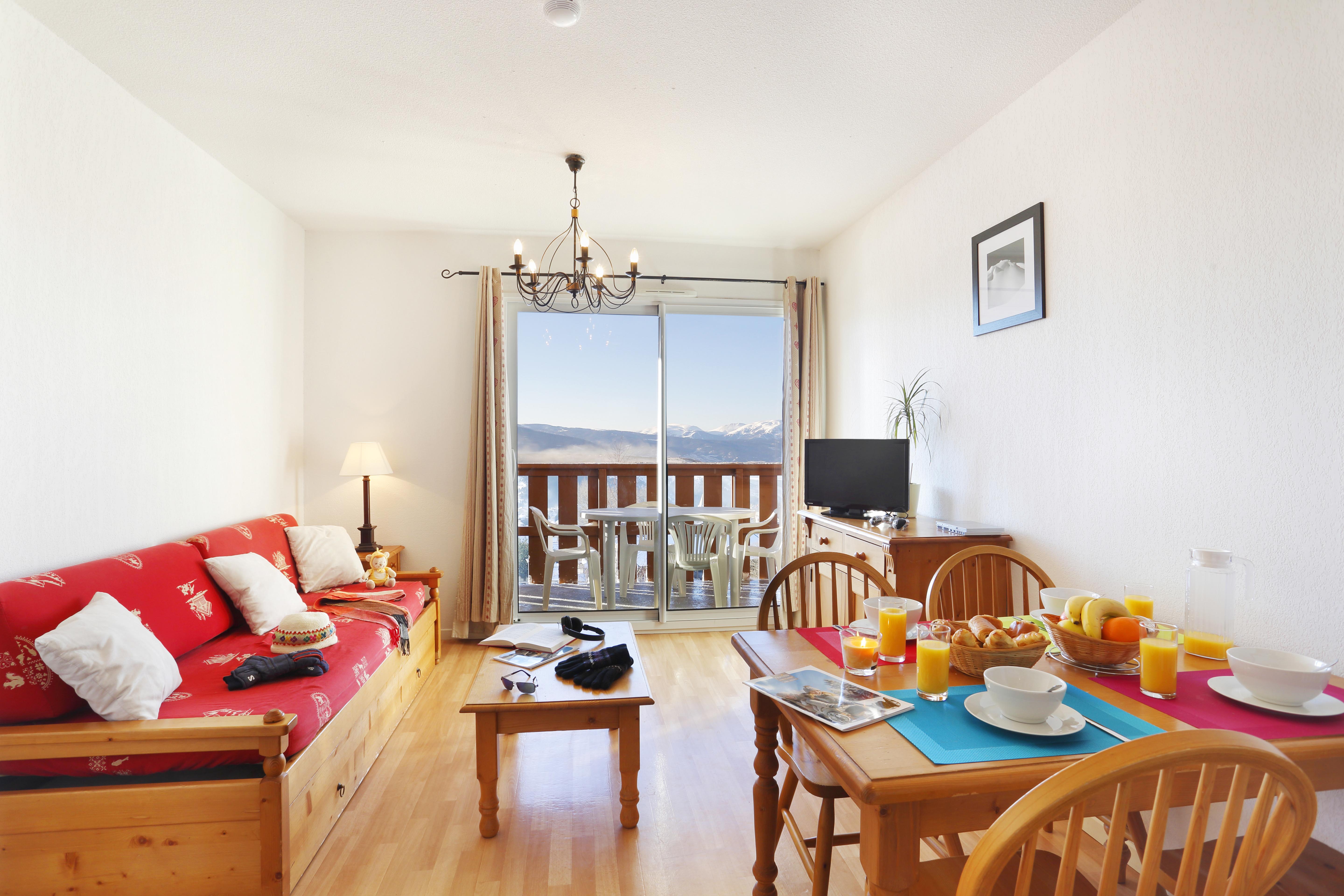 image Slide open the balcony doors from the living room to a dining table set beneath snow-capped peaks