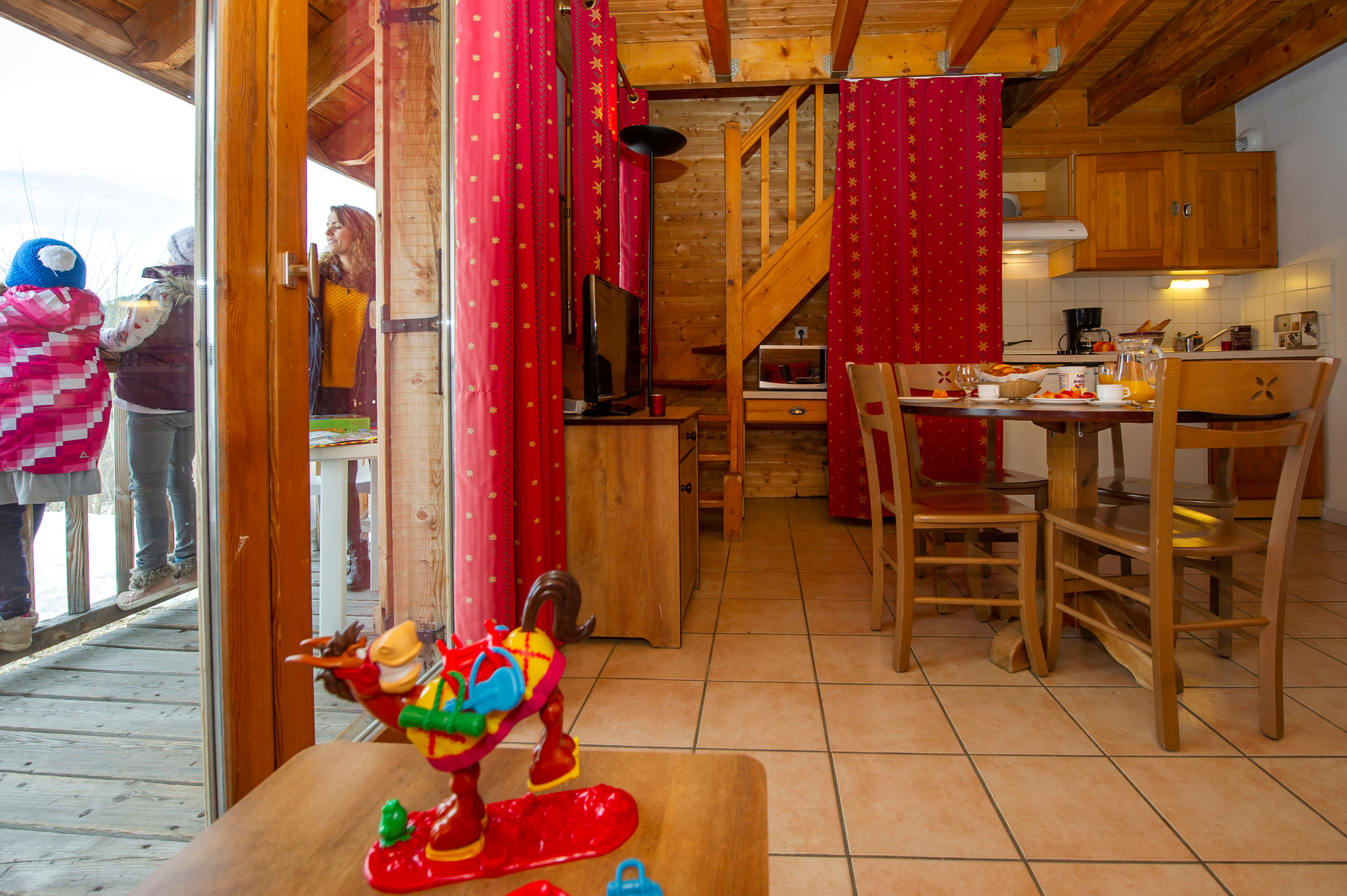 image The kitchen's wooden cabinets sit beside a dining table set for four, with a staircase leading to the upper level.