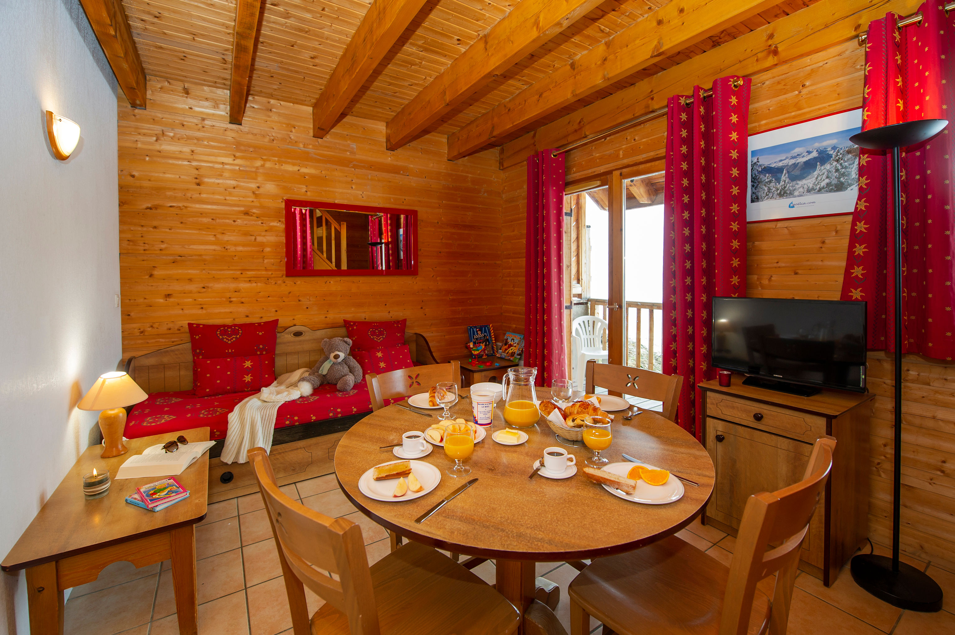 image Breakfast is set on the round dining table, with a trundle sofa bed and balcony doors just beyond.