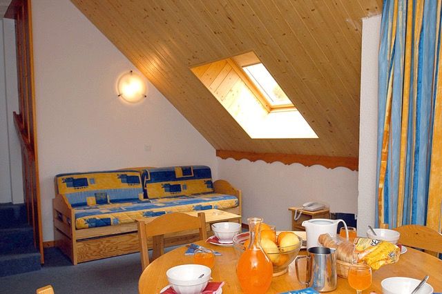 image Open-plan living space with a trundle sofa bed and dining table for two.