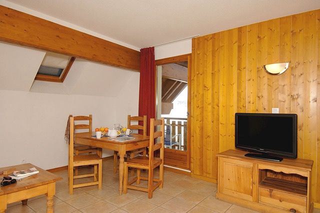image Sofa area opens onto the kitchenette, with wooden cabinetry throughout.
