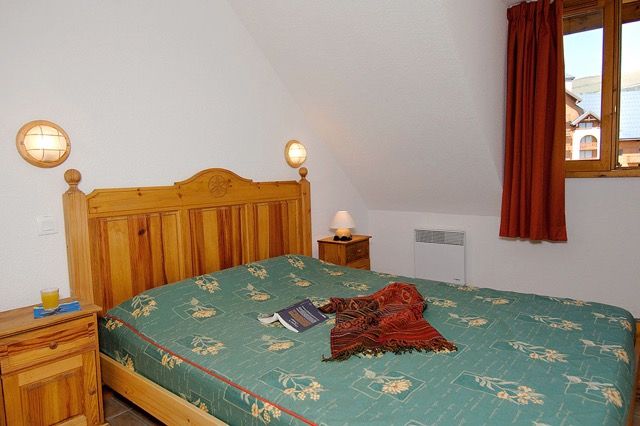 image Bedroom under a sloped ceiling, with a wooden bed frame and floral bedding.