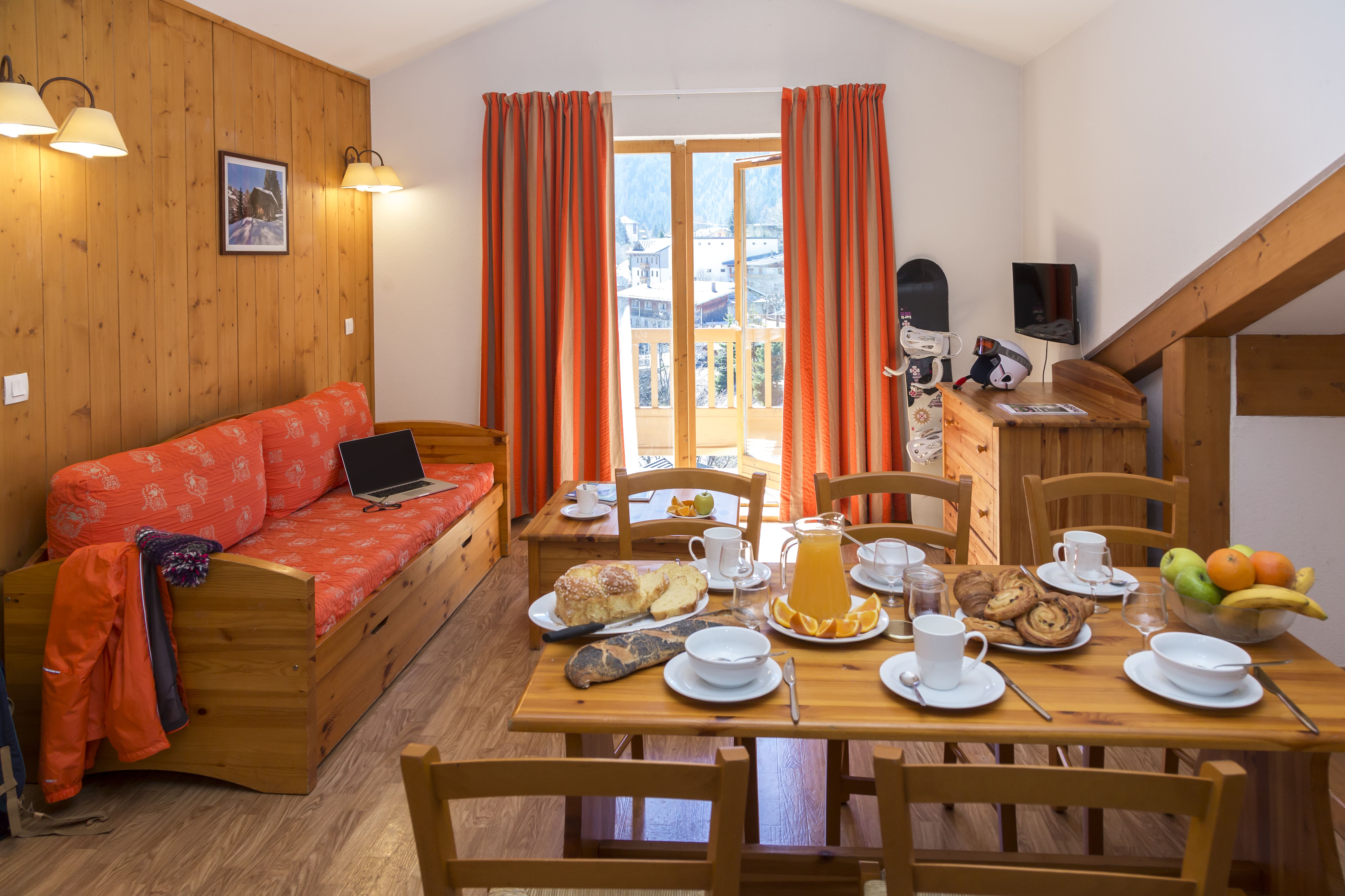 image The red sofa and dining table, laid for breakfast beneath a framed print.