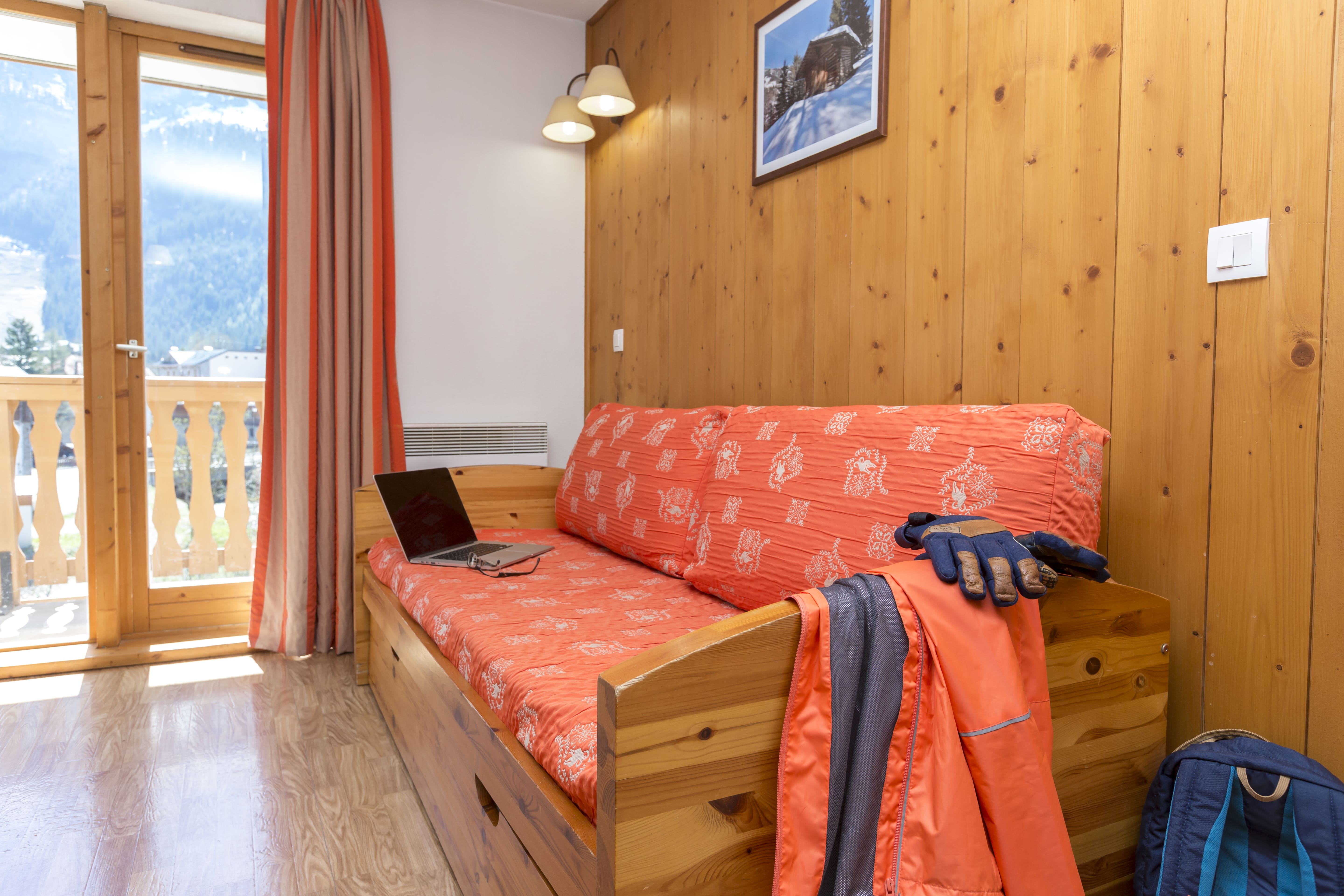 image Wood panelling runs across the walls, with red bedding adding warmth.