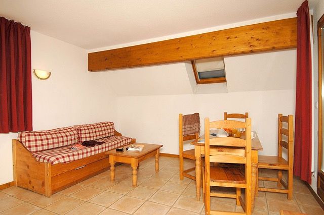 image Checkered sofa and dining table sit on light tile flooring under wood accents.