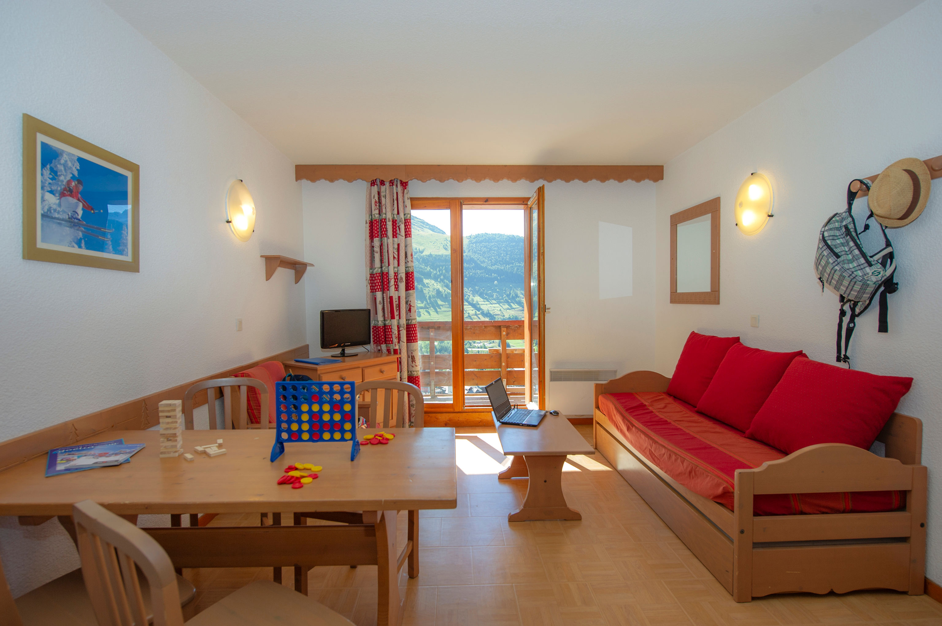image Living room with a red sofa, dining table and door to the balcony.