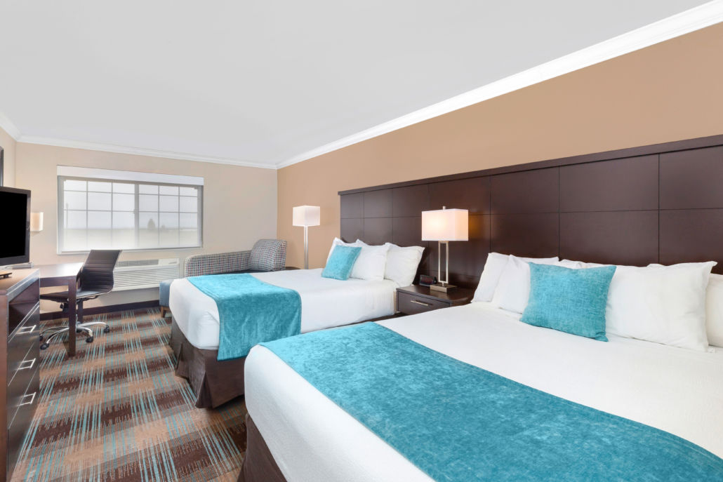 image Double queen room with two beds, desk, and recliner chair