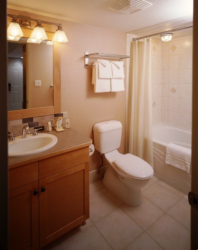 image The lovely bathroom features wooden touches along with a shower-tub combination.