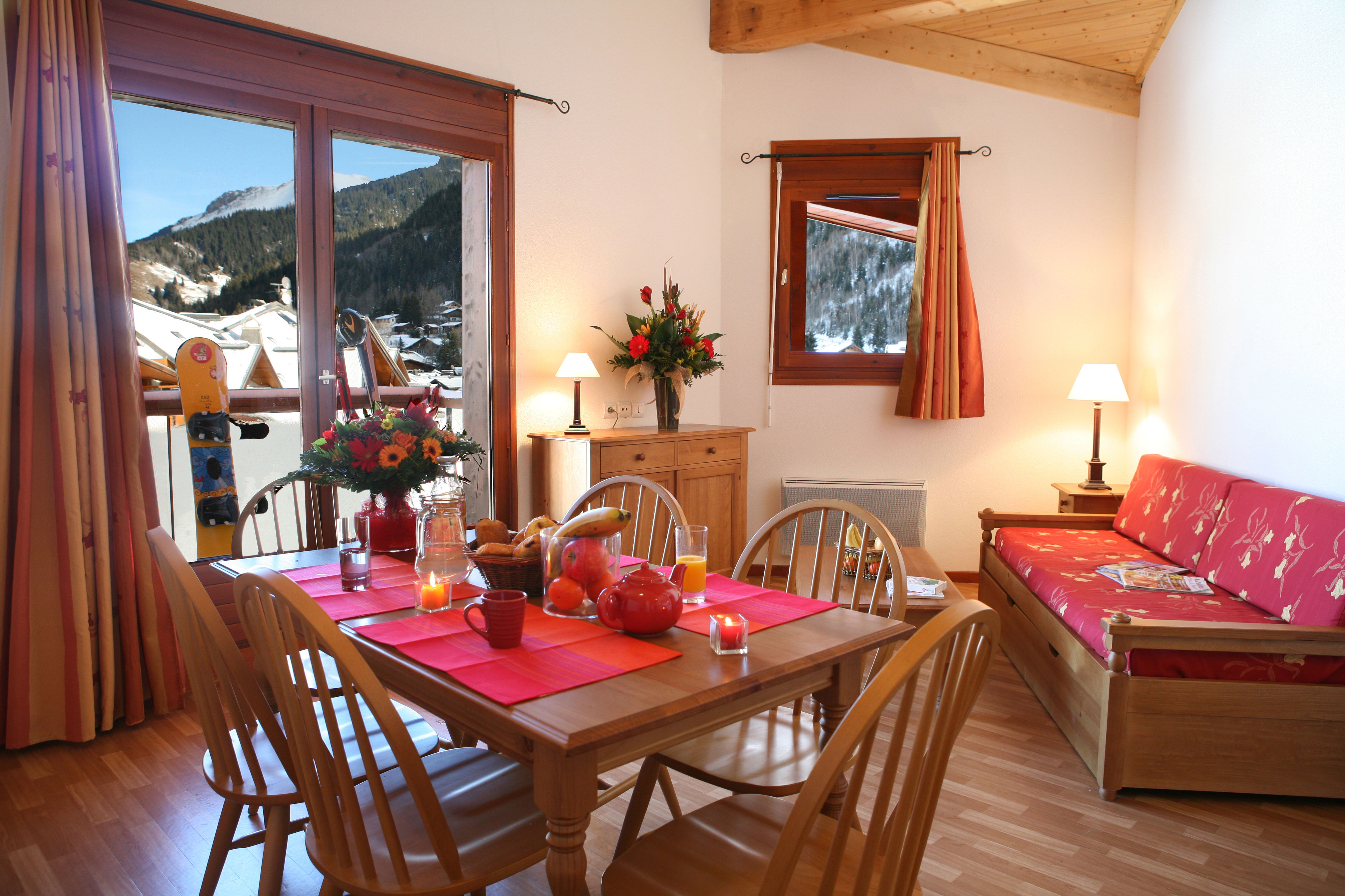 image A snowboard waits on the balcony, mountains and pine trees standing guard beyond.