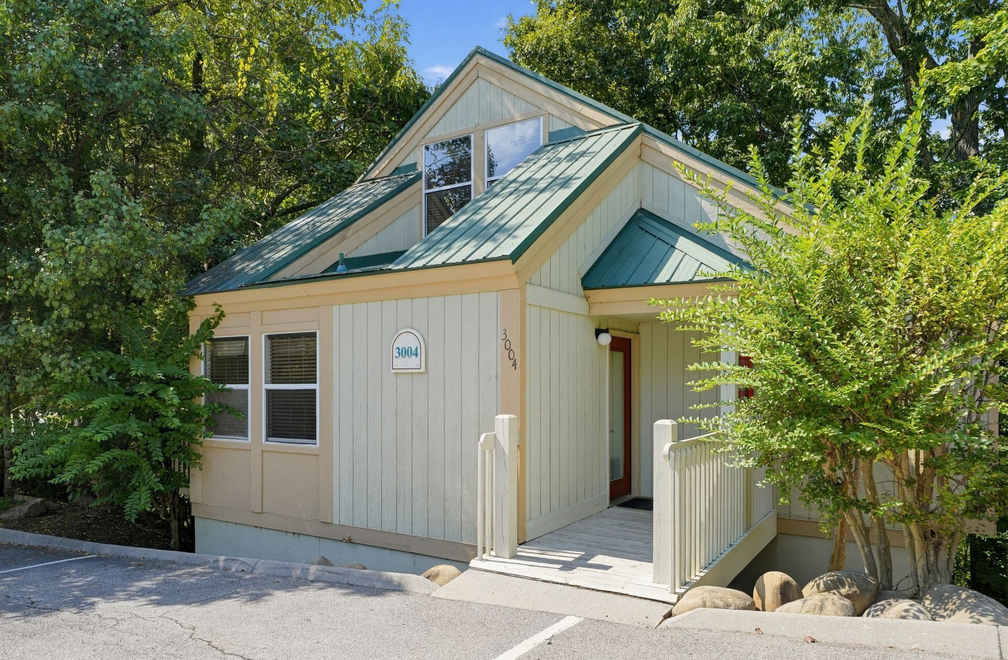 image Cabin exterior with green roof and surrounding trees