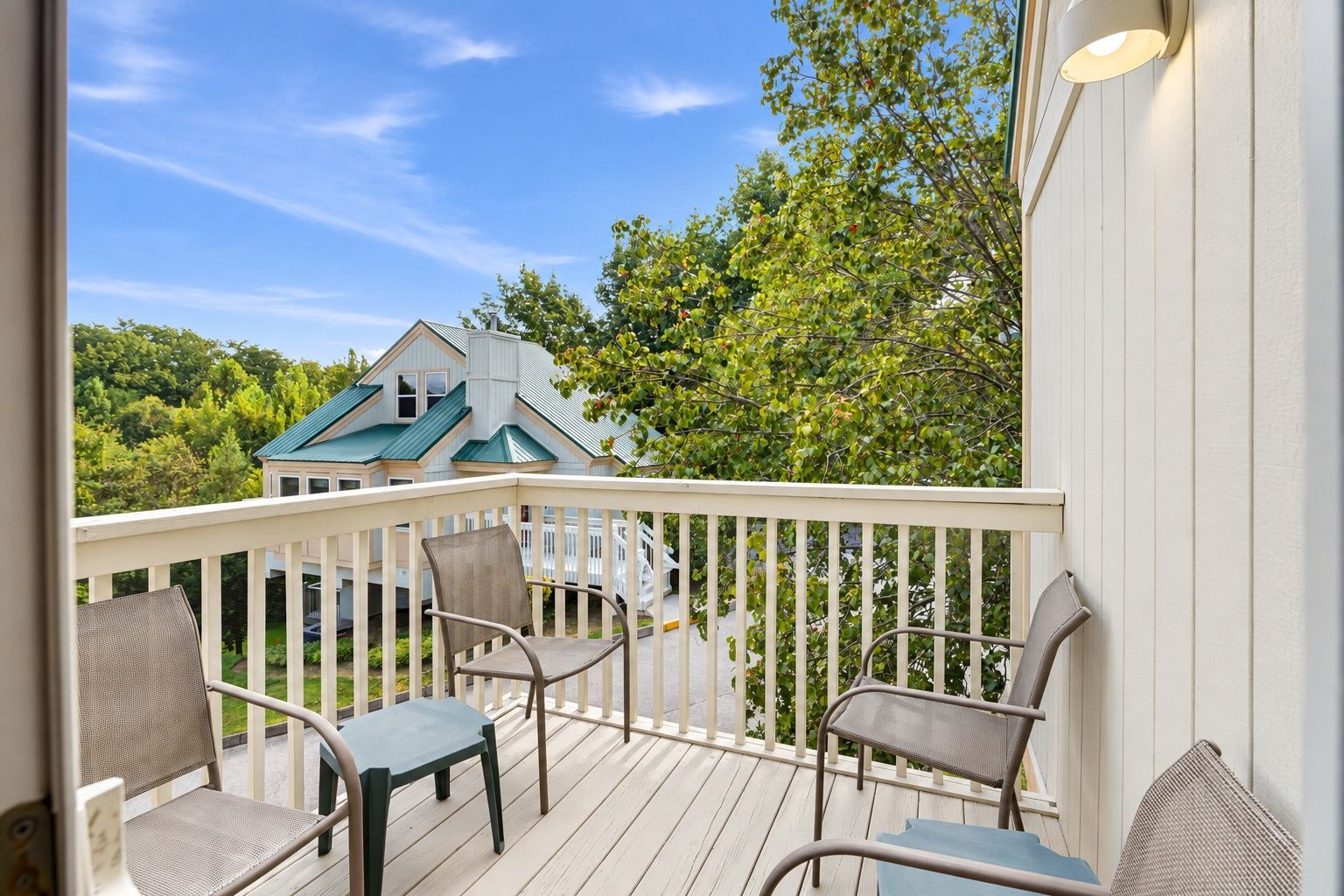 image Private balcony with patio chairs and a railing overlooking trees.