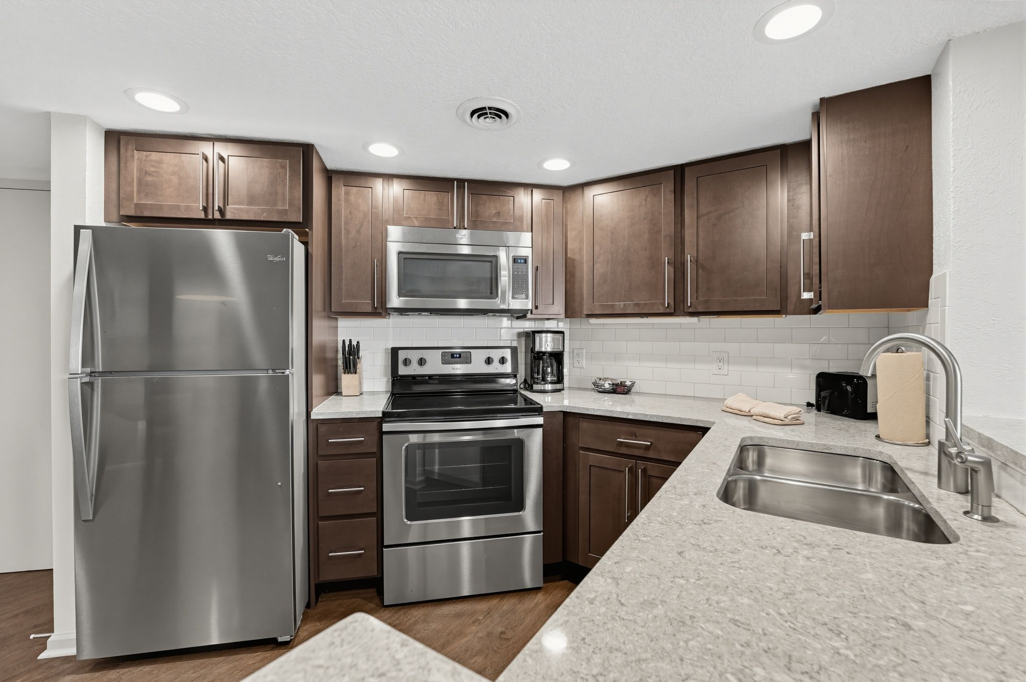 image Kitchen with a stainless steel refrigerator, range, and microwave, dark cabinets, and light countertops.