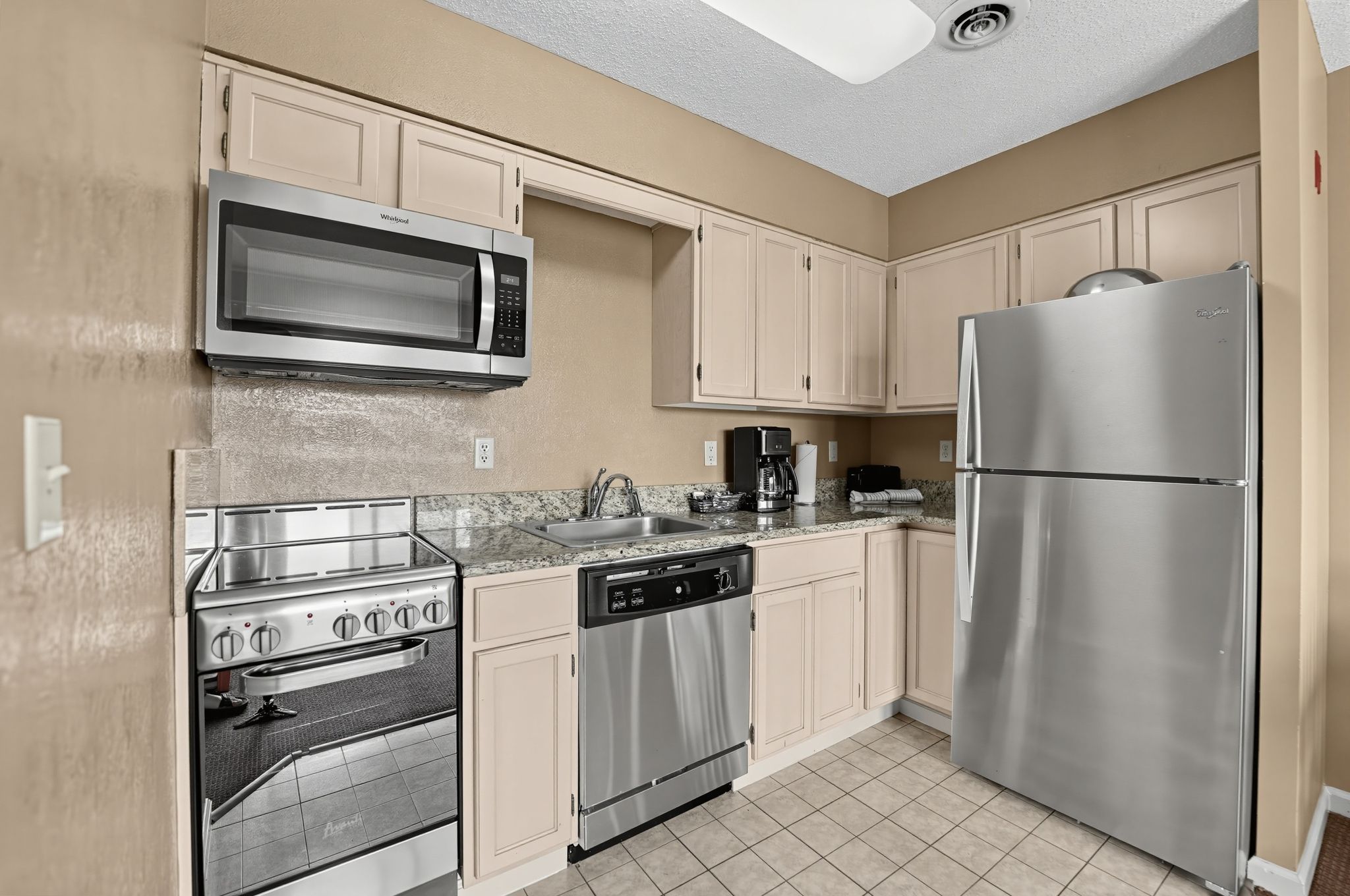 image Kitchen with a stainless steel refrigerator, dishwasher, range, and microwave, and a double sink.