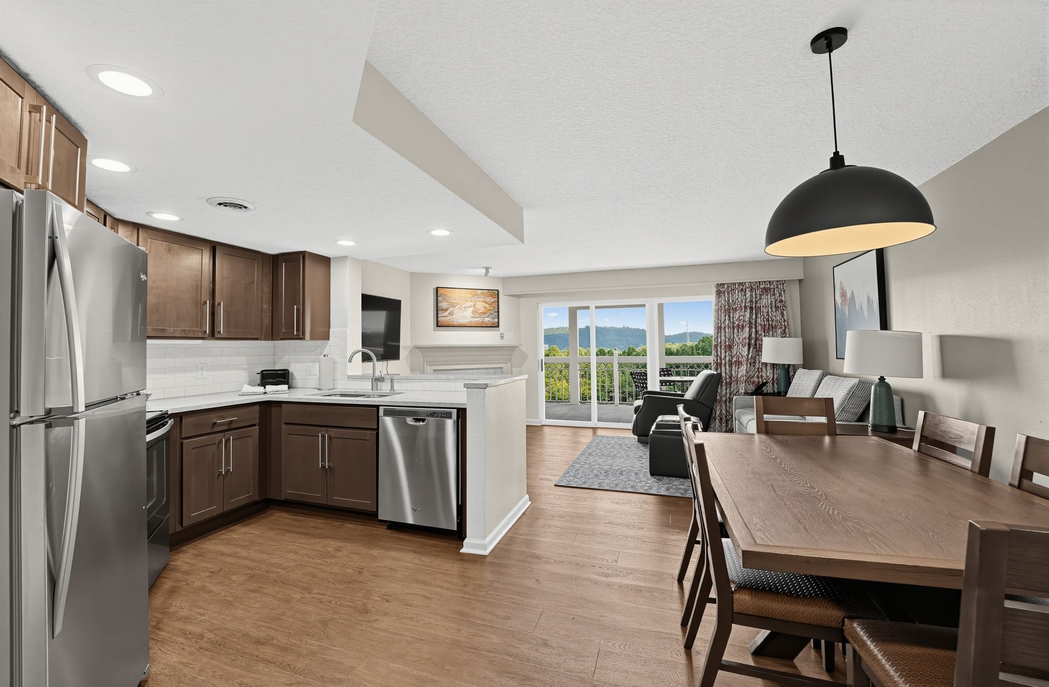 image Open kitchen, dining table, and living area with sliding doors to the balcony and a view.