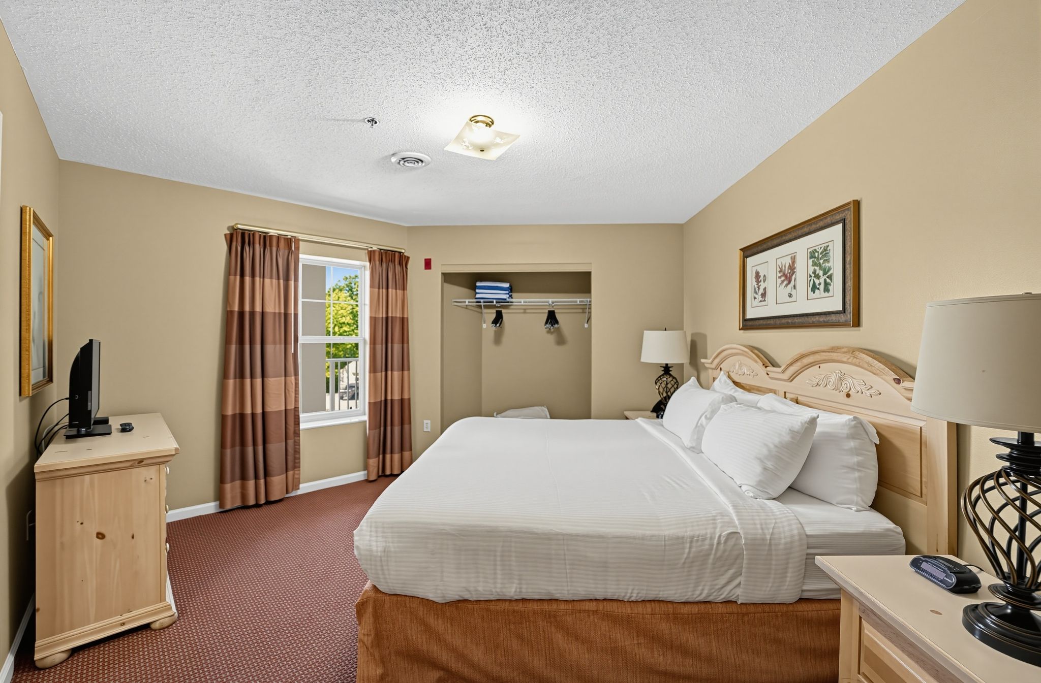 image Bedroom with a large bed, TV on a dresser, a window, and a closet.