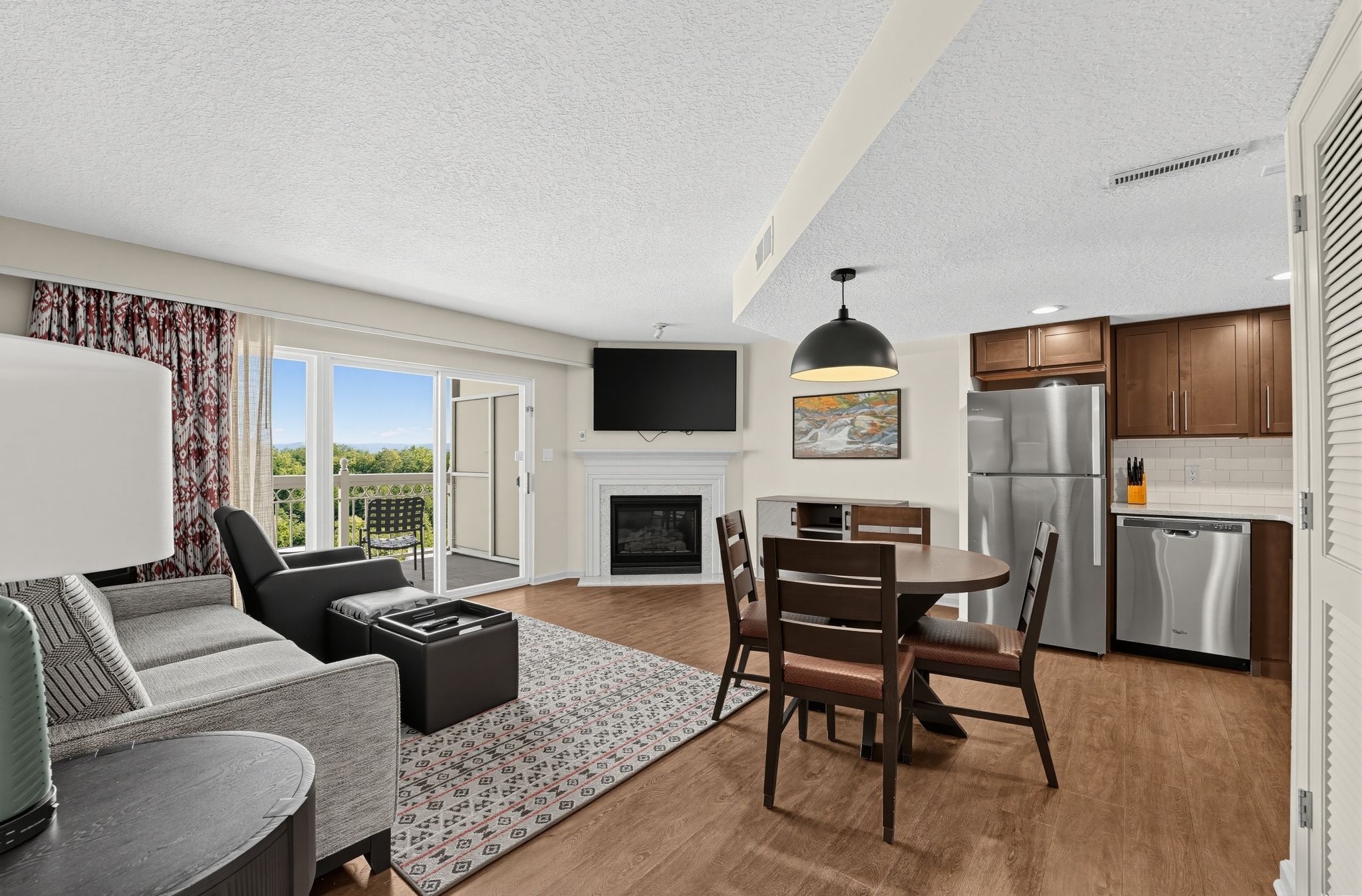 image Open living and dining area with a fireplace, TV, round dining table, and kitchen.