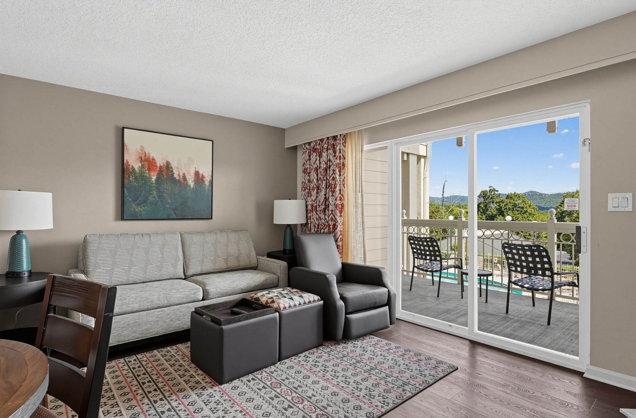 image Living room with a sofa, recliner, and ottoman, with sliding doors to a balcony and mountain views.