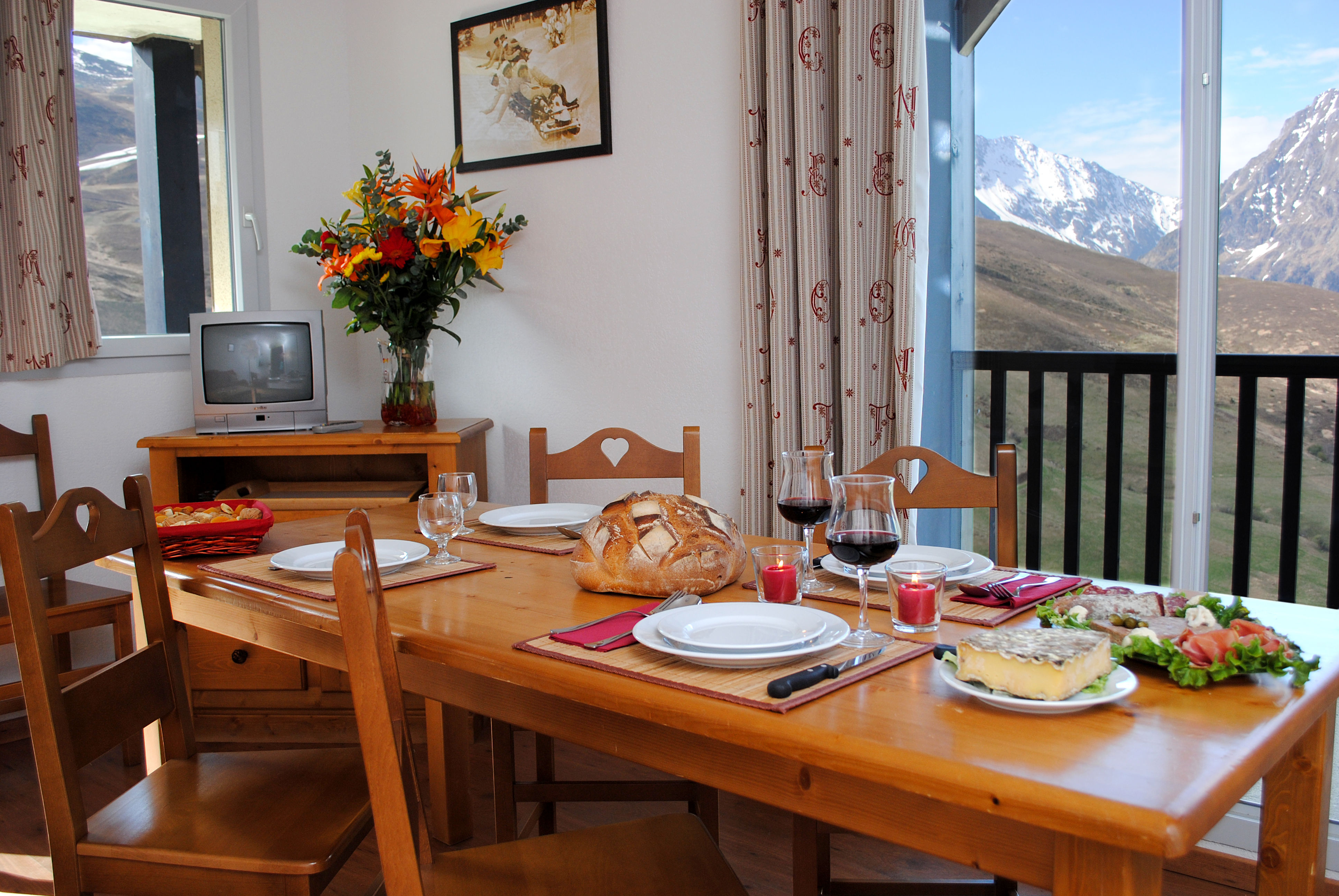image Dining area with plates, wine, bread, and a view of the mountains