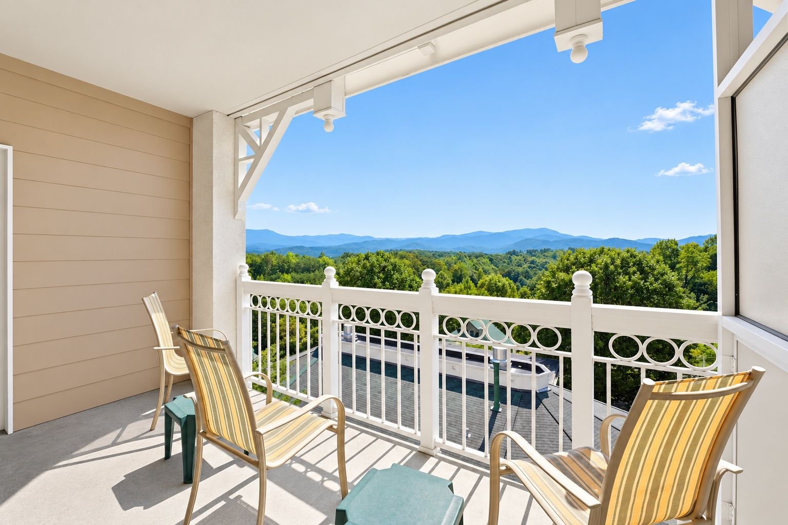 image Balcony with lounge chairs overlooking green hills and distant mountains.