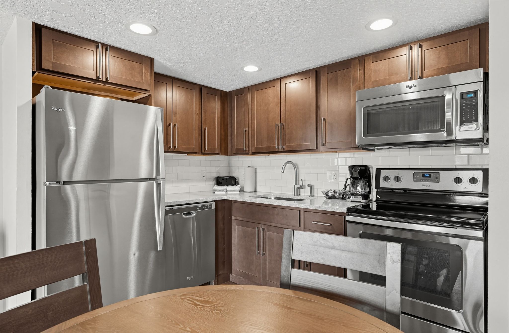 image Kitchen with a stainless steel refrigerator, range, dishwasher, and microwave, and dark cabinets.
