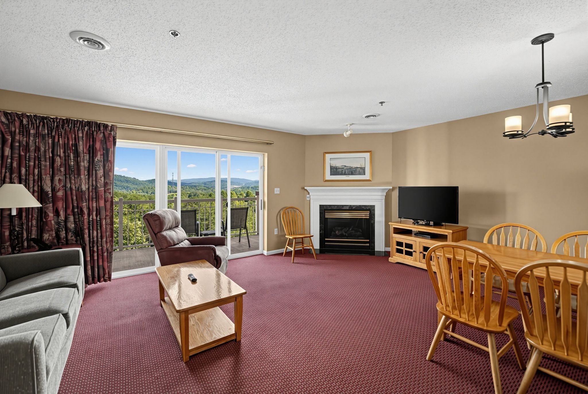 image Living and dining area with a fireplace, TV, and sliding doors to a balcony with mountain views.